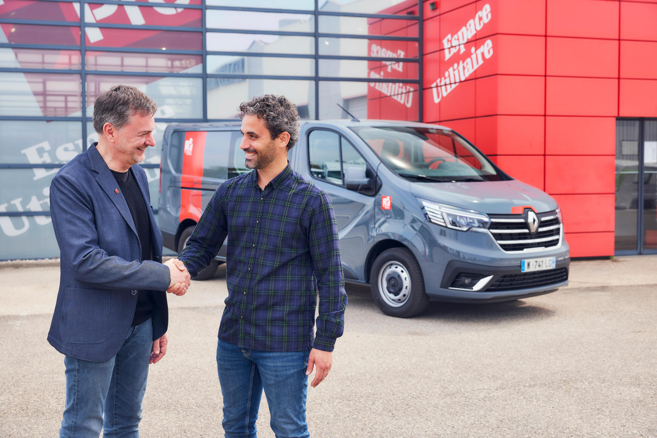 salesman and customer shaking hands in front of Renault Trucks Trafic