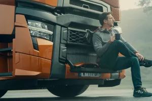 Model year 2025 : Renault Trucks T High Smart Racer : lifestyle (driver sitting on the windscreen access steps, relaxing with a cup in his hands)(Renault Trucks Stoneware Mug)(Renault Trucks Hero Zip Hoodie)
